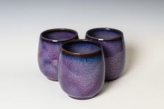 three purple cups sitting next to each other on a table