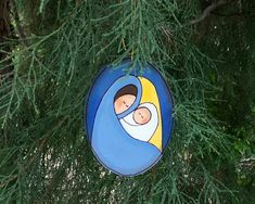 a blue ornament hanging from a tree with a nativity scene on it