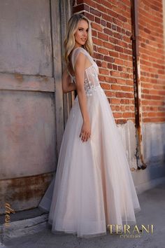 a woman standing in front of a brick wall wearing a white dress and high heels