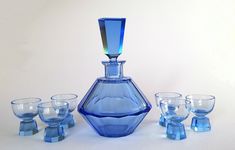 a blue glass vase sitting next to four glasses