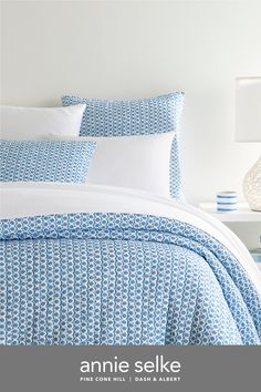 an image of a bed with blue and white comforters