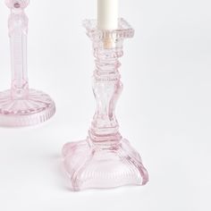 two glass candlesticks on a white background, one with a candle in it