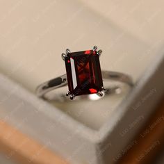 Red Emerald Cut Birthstone Ring, Emerald Cut Ruby Ring Gift, Elegant Emerald-cut Solitaire Ruby Ring, Emerald Cut Red Birthstone Ring, Garnet Emerald Cut Promise Ring, Classic Ruby Promise Ring With Radiant Cut, Emerald Cut Garnet Promise Ring, Classic Radiant Cut Ruby Promise Ring, Elegant Garnet Rings In Rectangular Shape