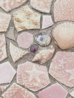 several seashells and other sea shells on a mosaic tile floor in pink tones