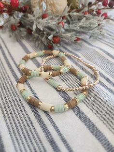 two bracelets sitting on top of a table next to a flower pot and christmas decorations