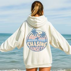 Sunset Hoodie, Beach Sweatshirt, Chasing Sunset Hoodie, Beach Sweatshirt, Summer Sweatshirt, Gift for Her, Beach Pullover, Beach Shirt This unisex heavy blend hooded sweatshirt is relaxation itself. Made with a thick blend of cotton and polyester, it feels plush, soft and warm, a perfect choice for any cold day. In the front, the spacious kangaroo pocket adds daily practicality while the hood's drawstring is the same color as the base sweater for extra style points. .: Made with a medium-heavy f Oversized Hooded Top For Vacation, Casual Vacation Hoodie Top, White Long Sleeve Sweater For Beach Season, Sporty Long Sleeve Sweatshirt For The Beach, Casual Relaxed Fit Hoodie For Vacation, Casual Hoodie With Relaxed Fit For Vacation, Beach Season Vacation Hoodie With Crew Neck, Vacation Hoodie With Relaxed Fit And Long Sleeves, Oversized Graphic Print Hoodie For Vacation