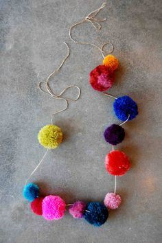 a colorful necklace with pom - poms hanging from it's sides on a gray surface