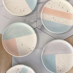 four plates with different designs on them sitting on a marble counter top next to each other