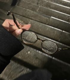 a person is holding up their glasses on the stairs