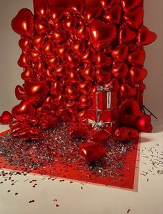 a red gift box sitting on top of a table next to confetti