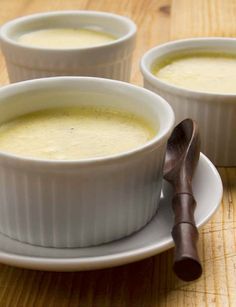 three white bowls filled with soup on top of a wooden table