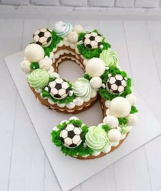 a cake decorated with soccer balls and greenery on top of a white tablecloth