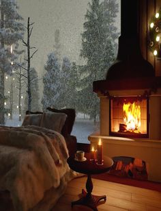 a cozy bedroom with a fireplace and christmas tree in the window, lit by candles