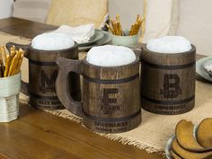 three wooden mugs sitting on top of a table next to plates and silverware