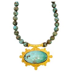 Vibrant turquoise and yellow gold beaded necklace bursting with color. This amazing piece makes an absolutely gorgeous statement on the neck. Featuring a single strand of round natural turquoise beads, each varying slightly in color and pattern, making this truly a one of a kind piece. Hanging off the center of the necklace is an oversized, ornately carved brushed yellow gold pendant, accented with a large single bezel set oval cabochon turquoise stone. This bold, colorful piece will not go unno Luxury Gold Turquoise Necklace With Round Beads, Artisan Gold Turquoise Pendant Necklace, Artisan Gold Turquoise Necklace With Natural Stones, Artisan Turquoise Necklace With Natural Stones In Gold, Gold Turquoise Necklace With Natural Stones In Artisan Style, Bohemian Single Strand Turquoise Necklace In Gold, Artisan Turquoise Beaded Necklace With Large Pendant, Artisan Gold Beaded Turquoise Necklace, Gold Beaded Turquoise Pendant Necklace