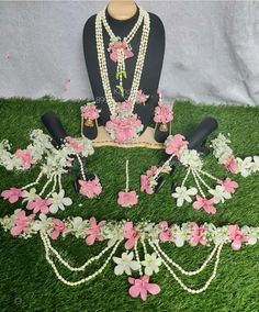 a mannequin with flowers and pearls on it sitting in the middle of grass