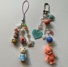 two key chains with charms attached to them on a white surface, one has an animal and the other has a heart