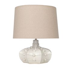 a white lamp with a beige shade on it's base and a light bulb in the shape of a flower