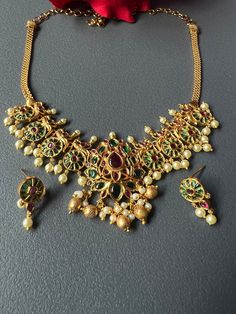 Antique Gold Premium Finished Peacock Emerald Kemp Necklace Set with matching Earrings South Indian Temple Jewelry. This item is perfect for parties and festivals! DETAILS: Includes one necklace and two earrings. Necklace: 14.5 total 19 .5 inches Long .Adjustable length. Chain closure. Weighs 1.45 oz (41 g). Earrings: 1.25 inch(es) long. Earring set weighs 0.30 oz (8 g). Earring backs push on/off. Material: Imitation gold, pearls, and red/green kemp stones. Finish: Premium antique matte gold fin Luxury Gold Temple Necklace With Peacock Design, Multicolor Peacock Design Temple Jewelry Sets, Elegant Multicolor Necklace With Peacock Design, Elegant Multicolor Peacock Design Necklace, Festive Green Jewelry Sets With Peacock Design, Traditional Party Jewelry Sets With Peacock Design, Elegant Gold Set With Peacock Design, Elegant Gold Sets With Peacock Design, Festive Multicolor Peacock Design Jewelry Sets