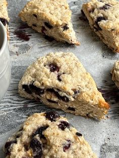 blueberry scones and a cup of coffee sit on a baking sheet next to each other