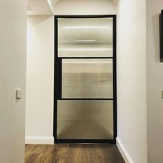 an empty room with a glass door and wood flooring on one side, and a television mounted to the wall