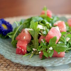 watermelon and arugula salad on a plate with blue flowers in the background