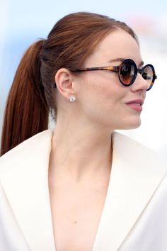 a woman with long hair wearing sunglasses and a white blazer is looking off to the side