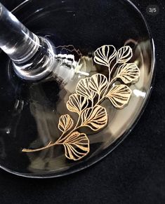 a wine glass with some gold flowers on it and a corkscrew in the middle