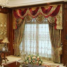 an elegant living room decorated in red and gold colors with floral curtains, chandelier, coffee table, vases and lamps