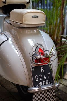 a white scooter with a black and white checkered license plate