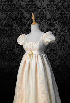 This is a beautiful Bridgerton-inspired dress in a beige and yellow jacquard fabric. It has a fitted bodice with a square neckline and puff sleeves. The skirt is full and gathered, with a yellow sash at the waist. The dress is perfect for a regency-themed event or party. Details: puffy sleeves, Ruched bodice, Cinnamon jacquard chiffon Length: Long (Dress length can be customized) Neckline: scoop Waistline: high-waisted Silhouette: A line Bridgerton Daphne, Antoinette Dress, 18th Bday, Regency Gown, Regency Era Fashion, Yule Ball, Regency Dress, Long Sleeve Gown, Regency Era