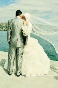 the bride and groom are standing by the water