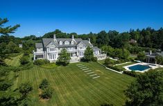 an aerial view of a large white house with a pool in the middle of it