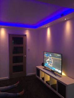 a person laying on the floor in front of a flat screen tv with blue lights