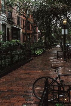 a bike parked on the side of a street next to a lamp post and trees