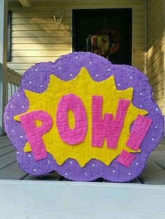 a purple and yellow sign with the word pow on it in front of a house