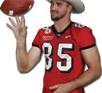 a man holding a football in his right hand and wearing a cowboy hat on top of it