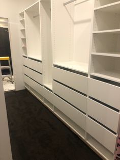 an empty room with white shelving and black carpeted flooring on the walls