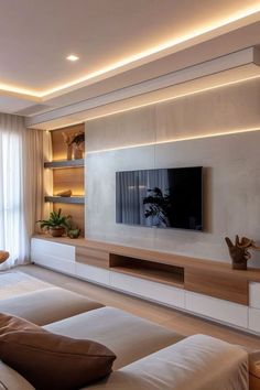 a modern living room with white walls and wooden furniture, including a large flat screen tv mounted on the wall