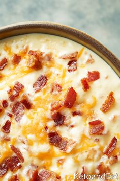 a close up of a bowl of food with cheese and bacon on it's surface