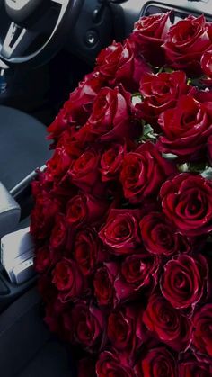 a bouquet of red roses sitting on the dashboard of a car