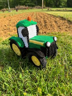 a crocheted toy tractor sitting in the grass