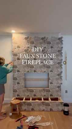 a woman standing in front of a stone fireplace with the words diy faux stone fireplace