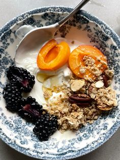 a bowl filled with granola, fruit and yogurt on top of a table