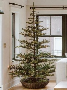 a living room with a christmas tree in the corner and a white couch next to it