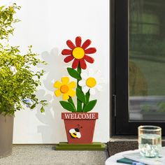 a welcome sign with flowers in a flower pot