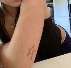 a woman with a small star tattoo on her arm, sitting in front of a counter