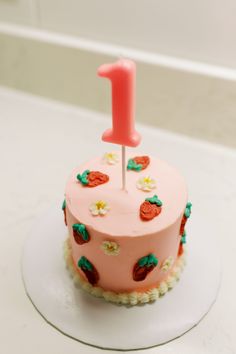 a pink birthday cake with a one candle on top