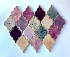 an assortment of different colored glass tiles on a white surface, arranged in the shape of a trellis