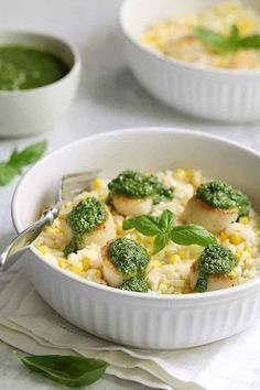 two white bowls filled with food and garnished with green leafy toppings